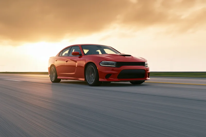 Red sport sedan driving fast on open highway at sunset