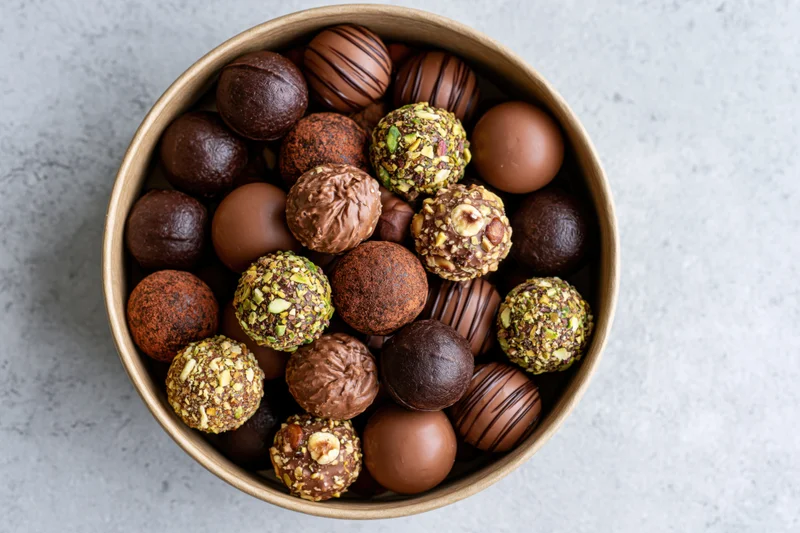 Assorted chocolate truffles in a round kraft paper gift box on a gray surface