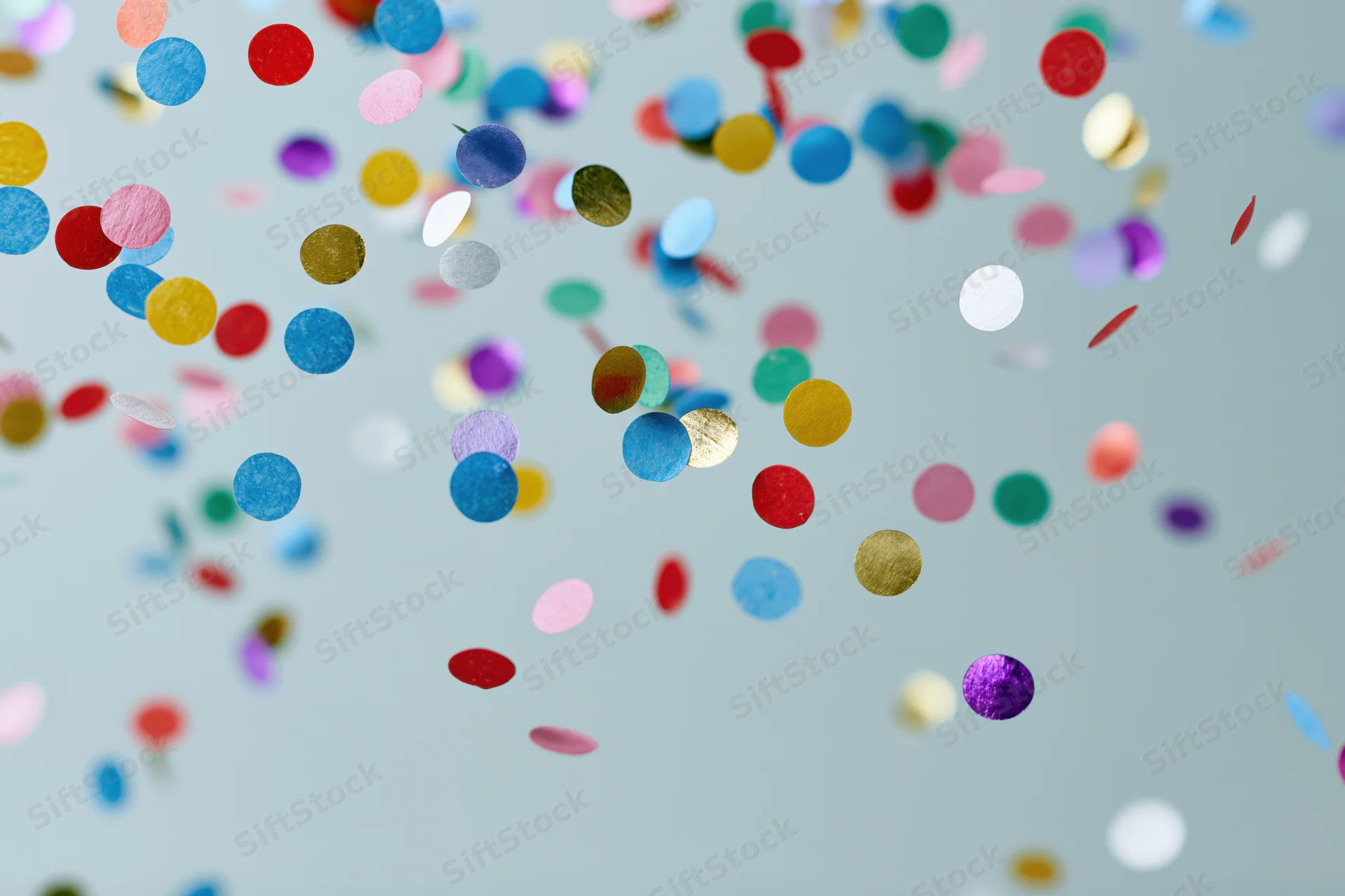 Round confetti pieces floating midair against a light blue background