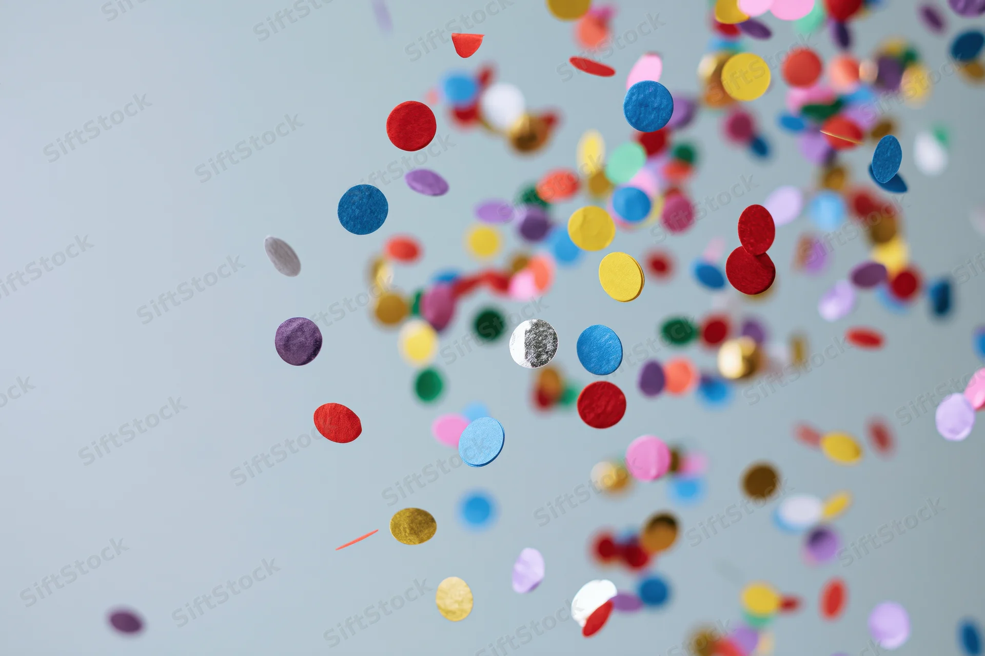 Round confetti pieces floating midair against a light gray background with copyspace on the left