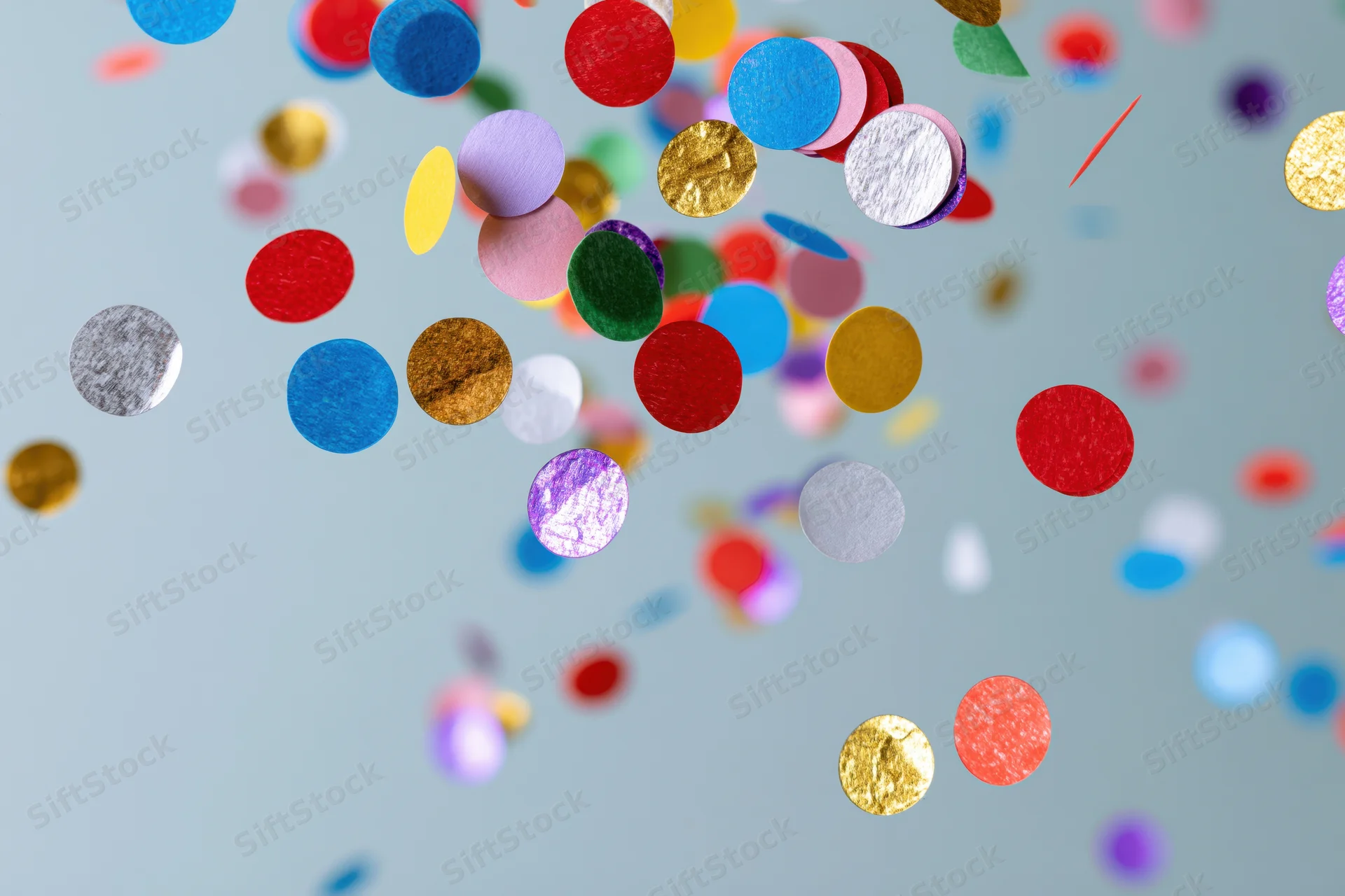 Round confetti pieces floating midair against a light blue background