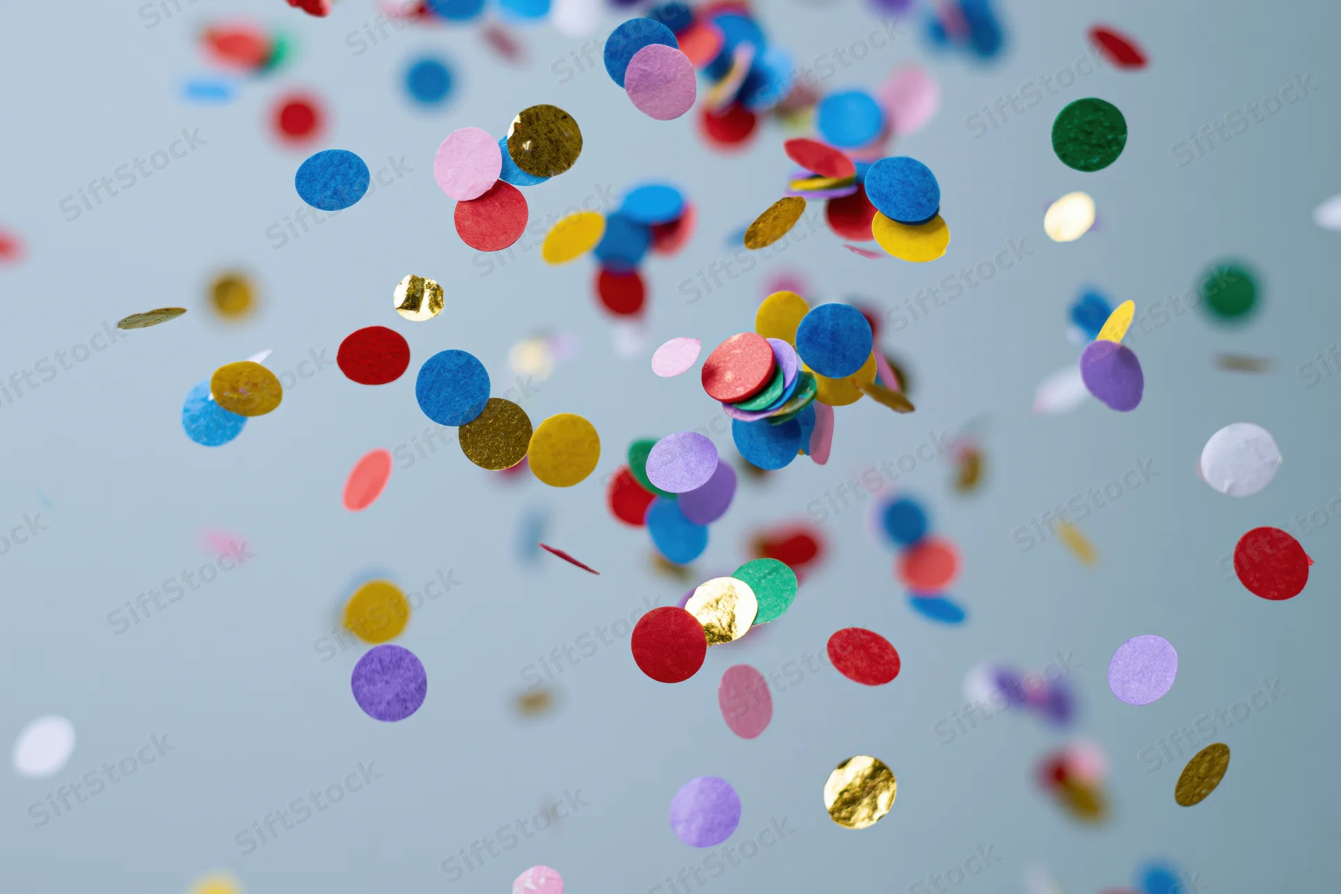 Round confetti pieces floating midair against a light blue background