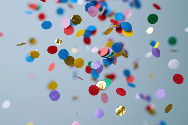 Round confetti pieces floating midair against a light blue background