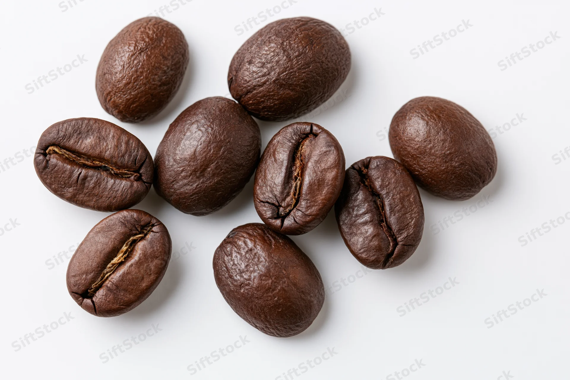 Dark roasted coffee beans scattered in loose clusters on white background