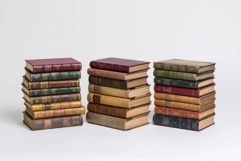 Three stacks of vintage hardcover books arranged in a row on a white surface