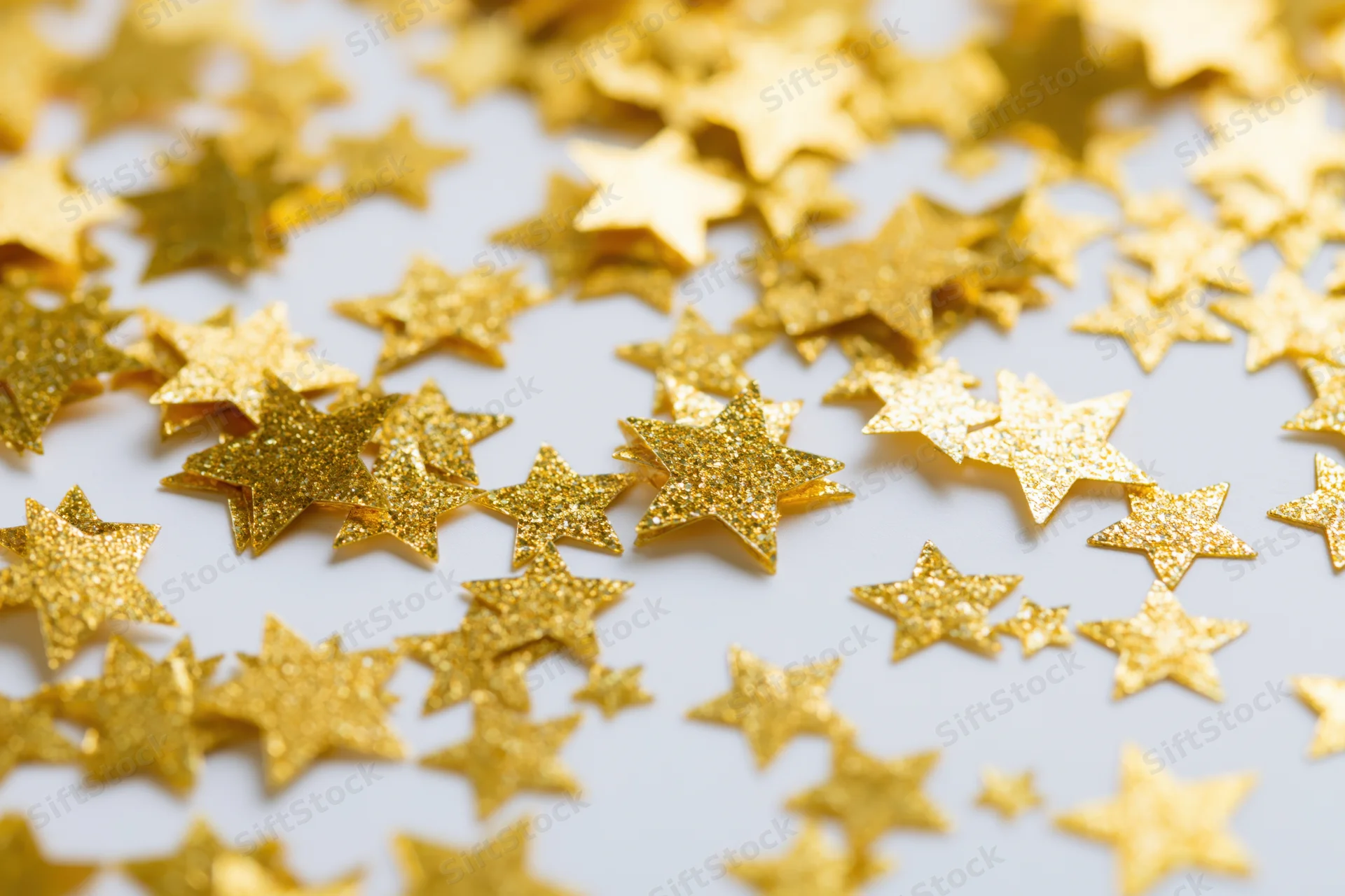 Gold star confetti scattered across a white surface