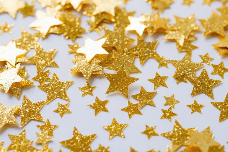 Gold foil star confetti scattered across a white surface
