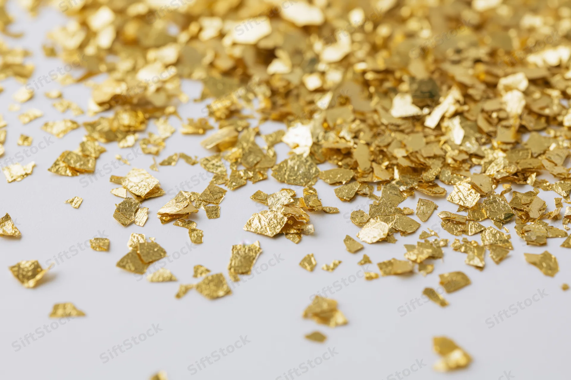 Scattered gold foil confetti pieces on a white surface