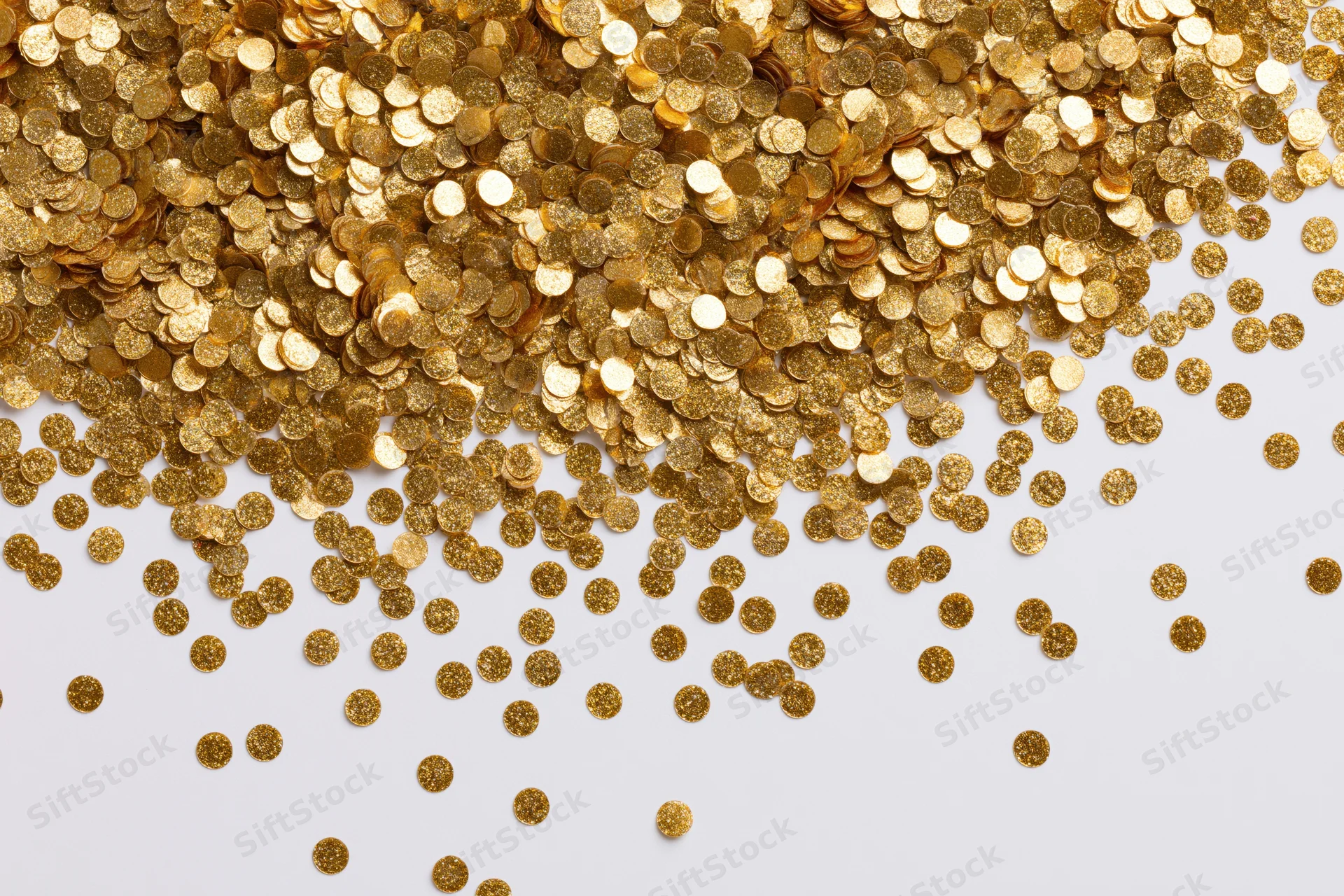 Gold confetti scattered across a white surface with copyspace
