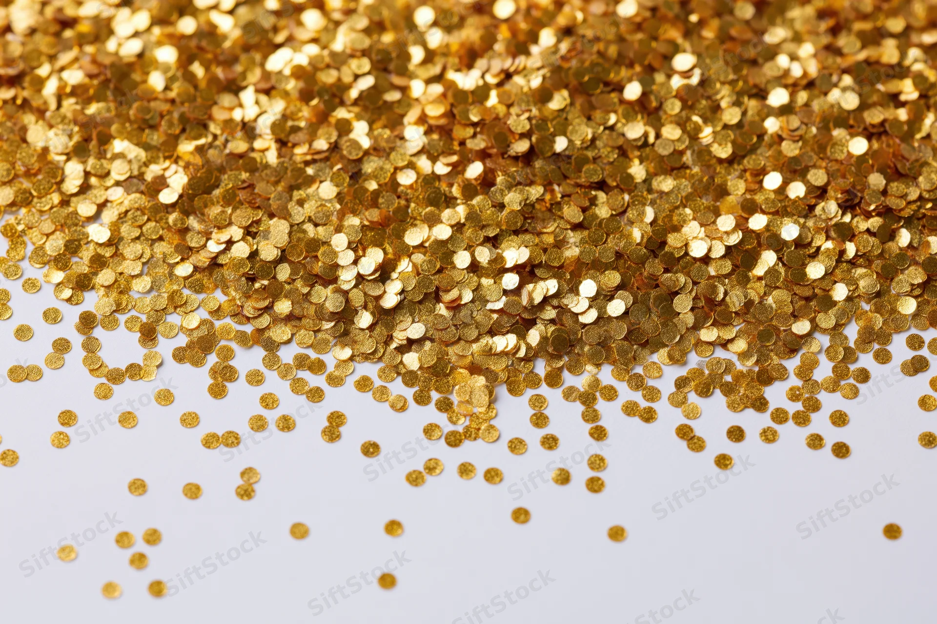 Gold confetti scattered across a white surface with copyspace