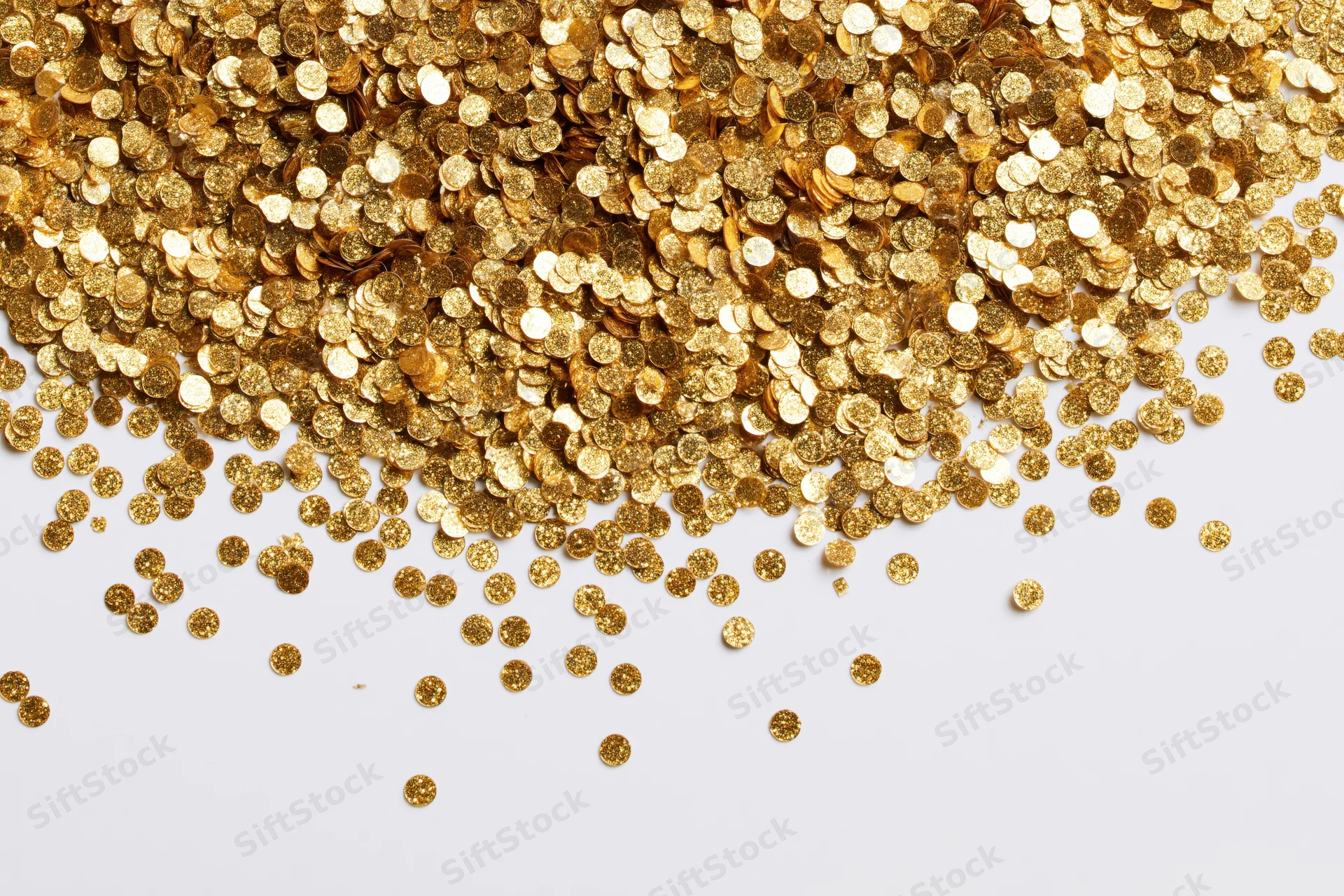 Gold confetti pieces scattered across a white surface with copyspace