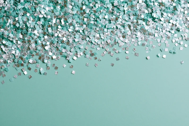 Square confetti pieces scattered densely at top on teal background with copyspace below