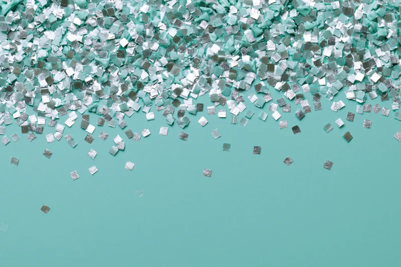Square silver and mint confetti scattered densely at top fading to sparse on teal background with copyspace below