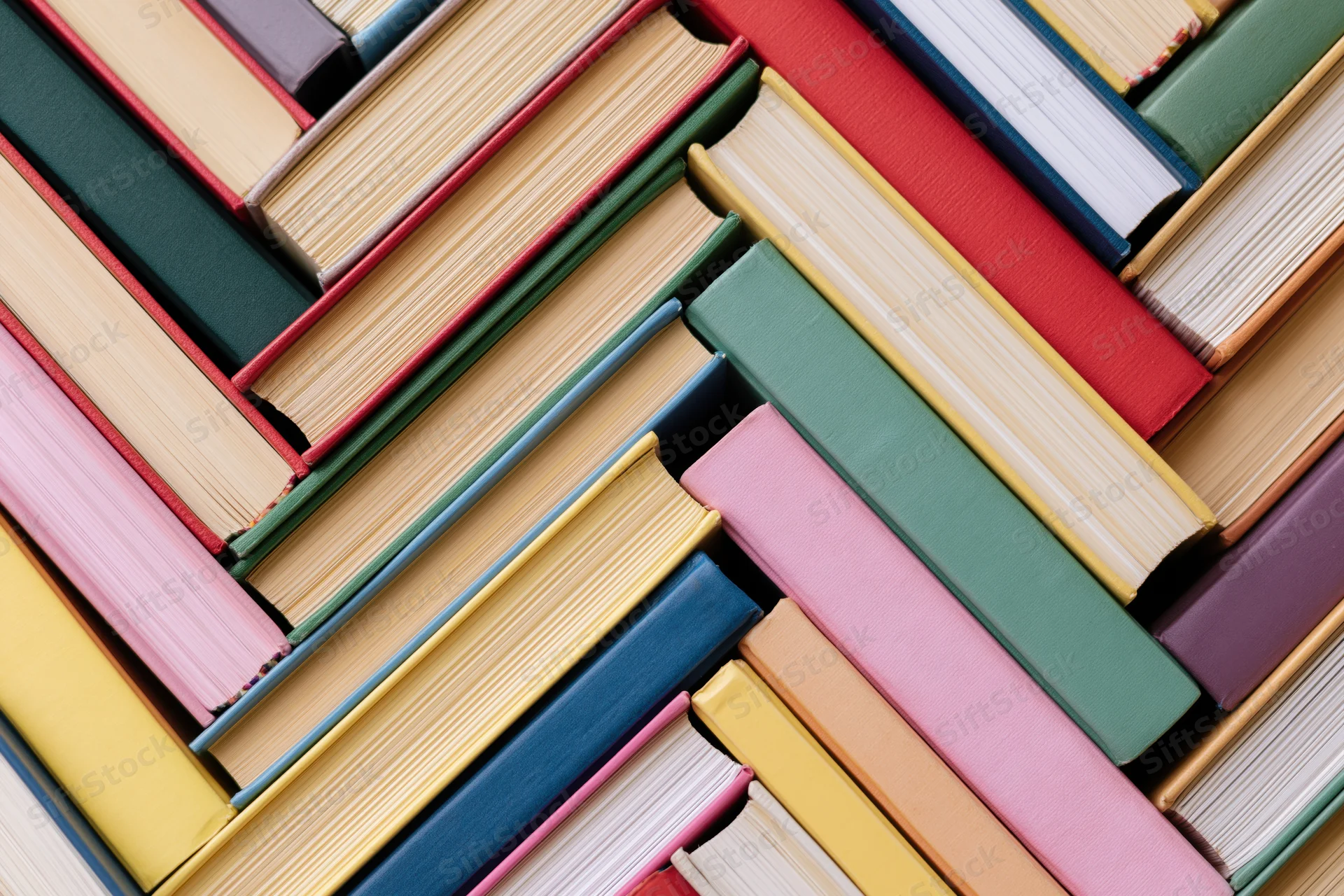 Hardcover books arranged in herringbone diagonal pattern on flat surface