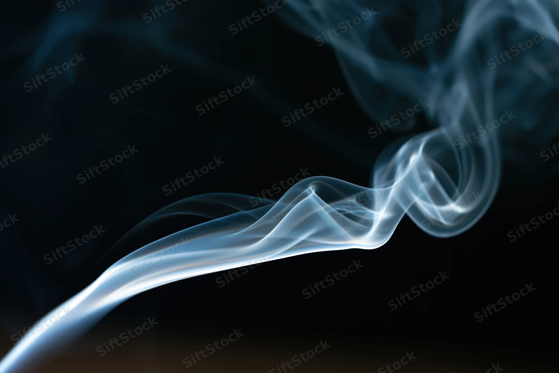 Thin wisp of white-grey smoke curling upward against a dark background