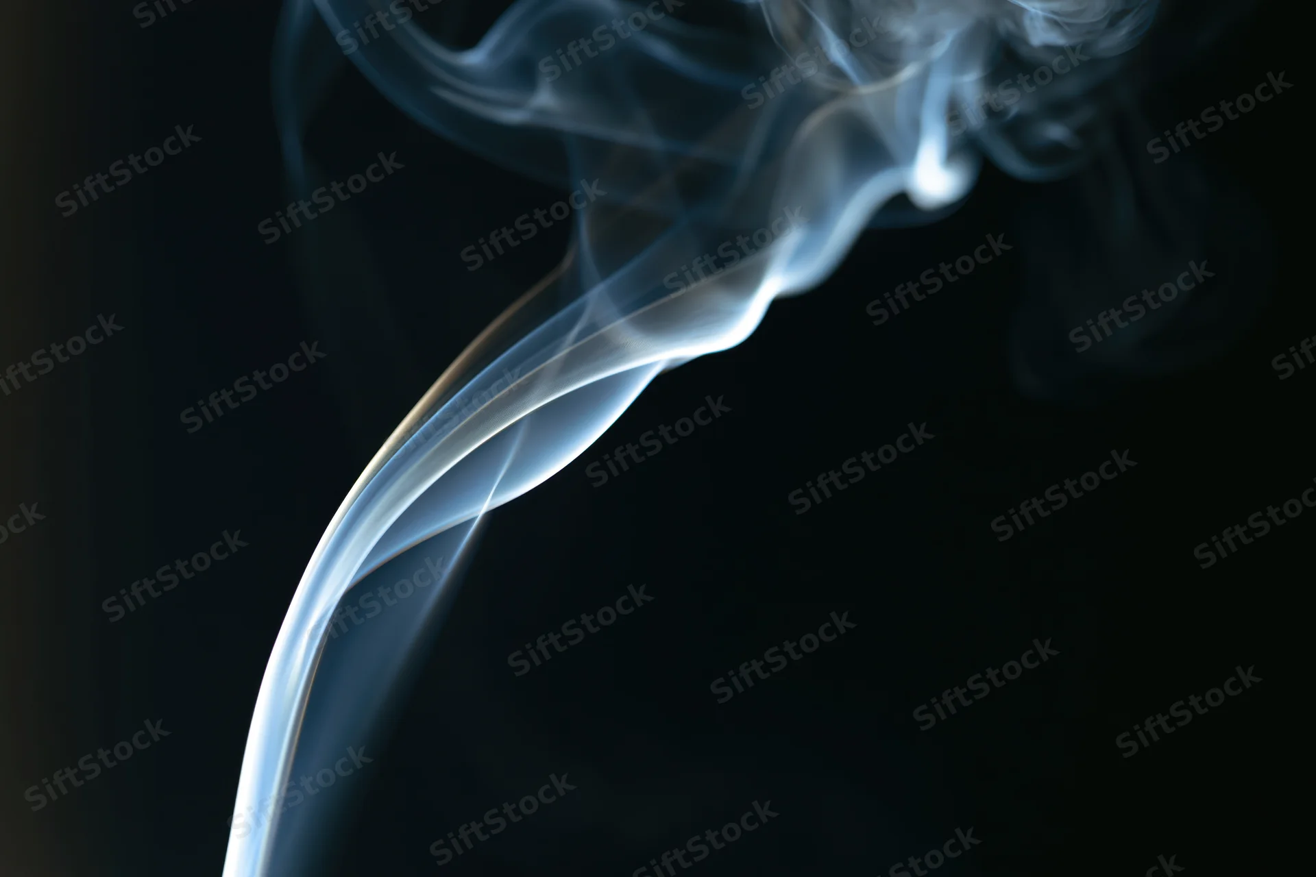 Thin wisp of white-grey smoke curling upward against a dark background