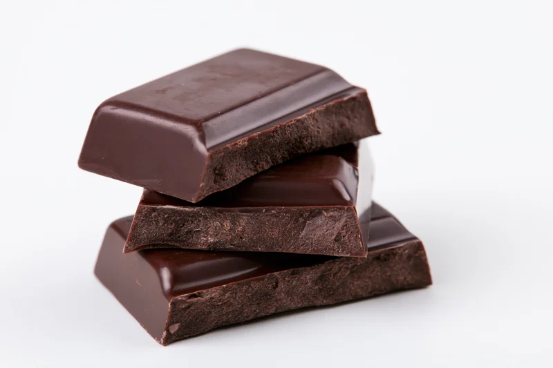 Three dark chocolate bar pieces stacked at a slight angle on white background