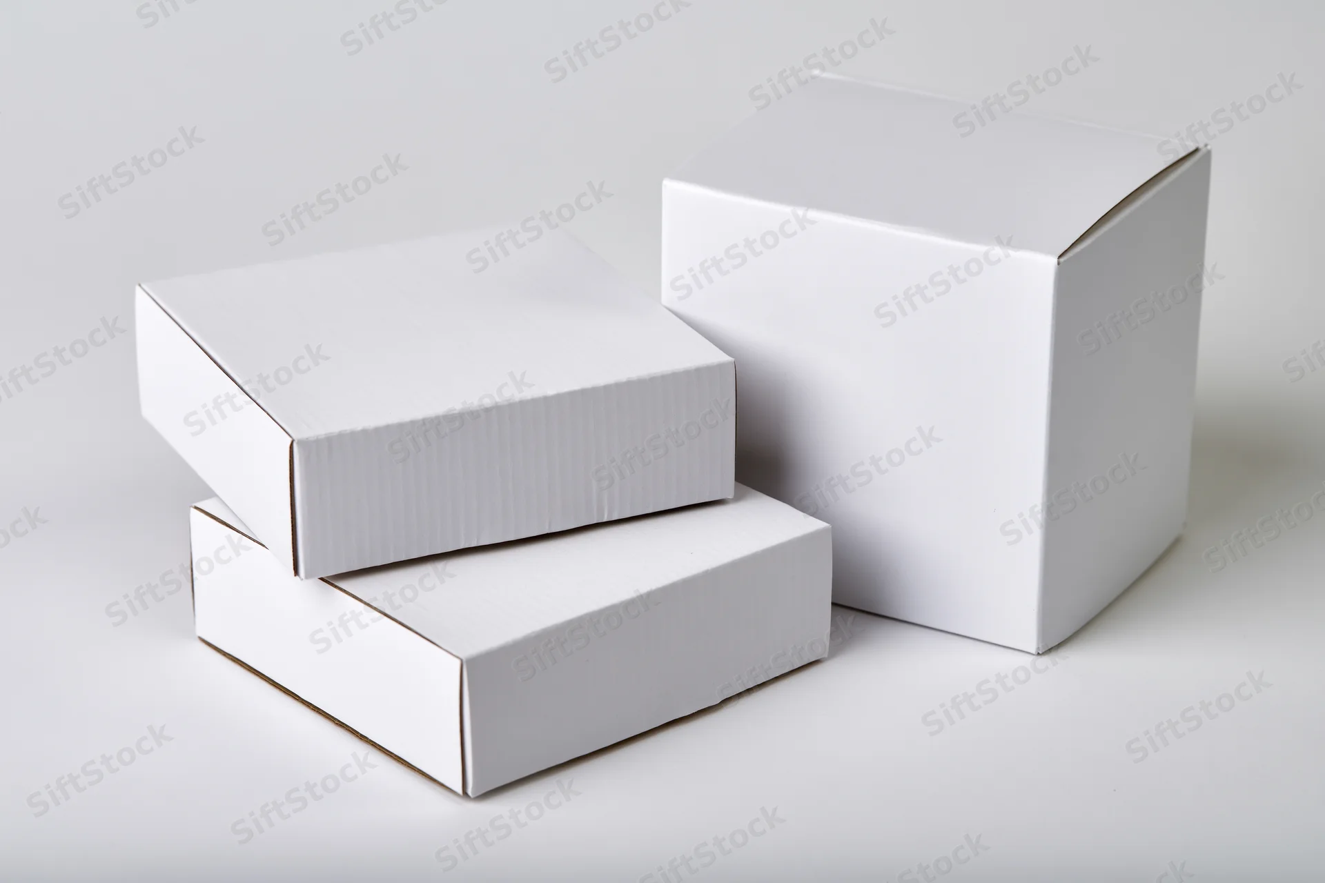Three plain white cardboard boxes arranged in a loose group on a white surface