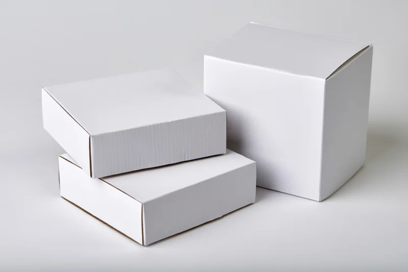 Three plain white cardboard boxes arranged in a loose group on a white surface