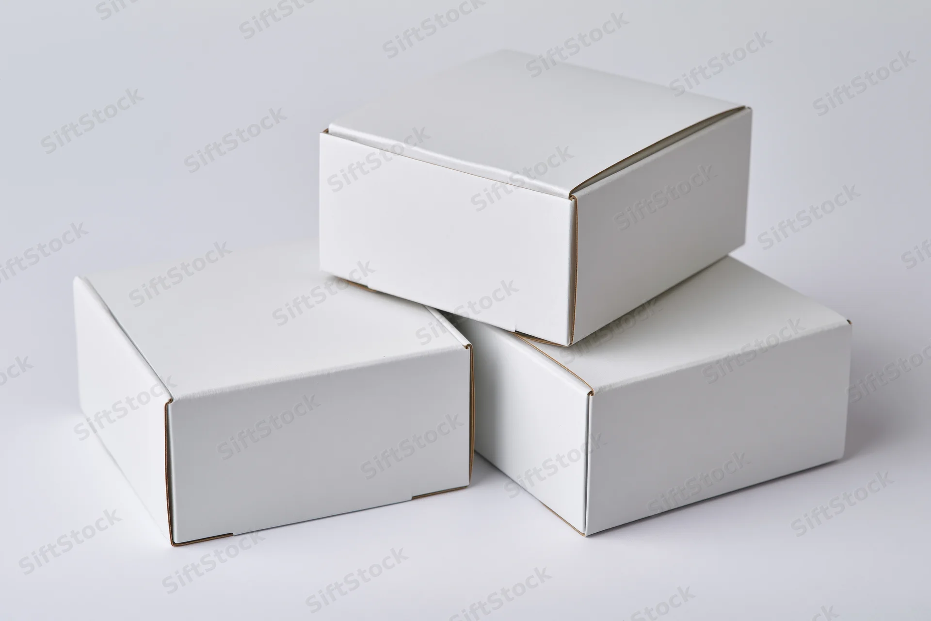 Three plain white cardboard boxes stacked in a loose arrangement on a white surface