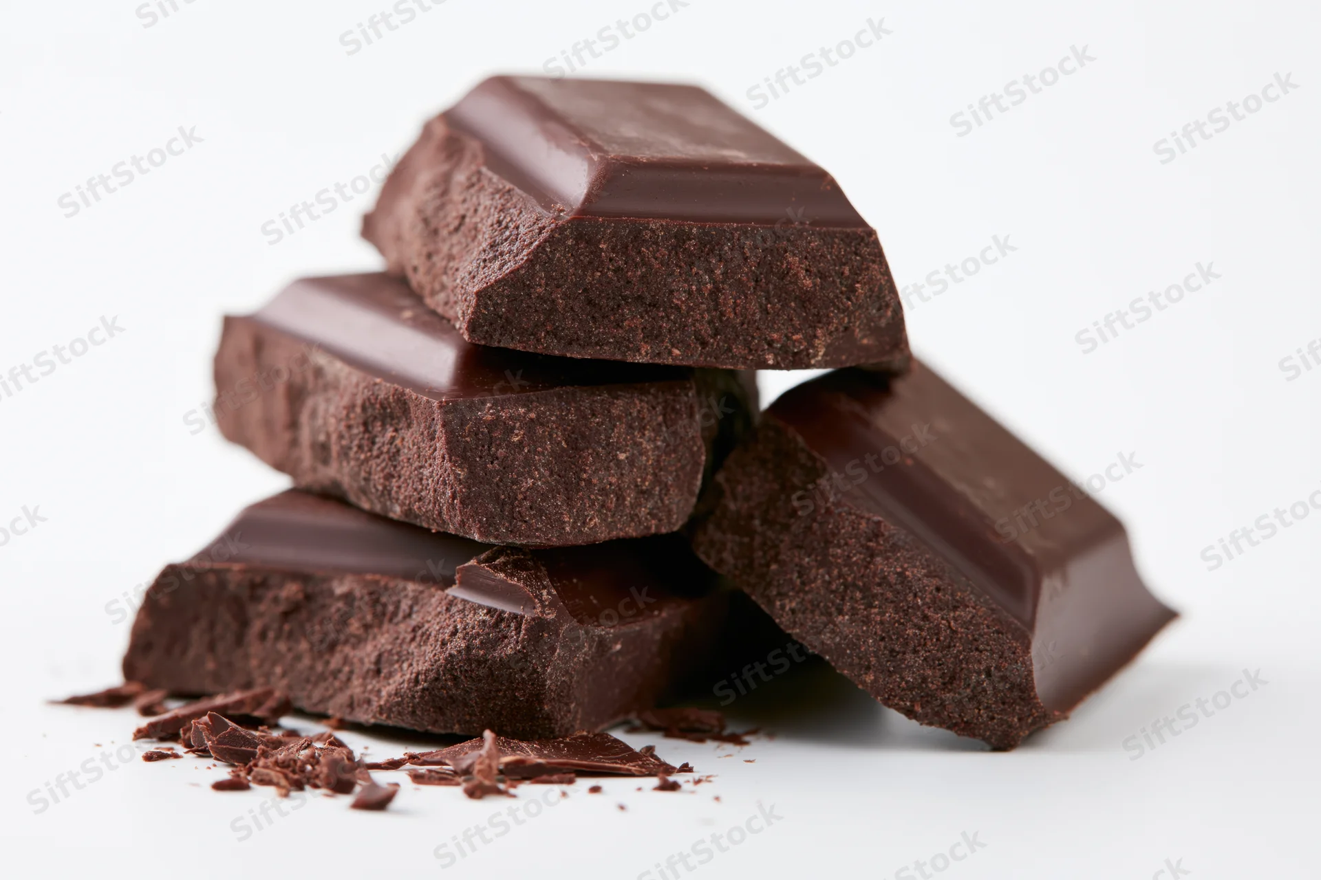 Broken dark chocolate pieces stacked loosely on white background
