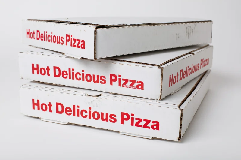 Three stacked white pizza delivery boxes with red printing