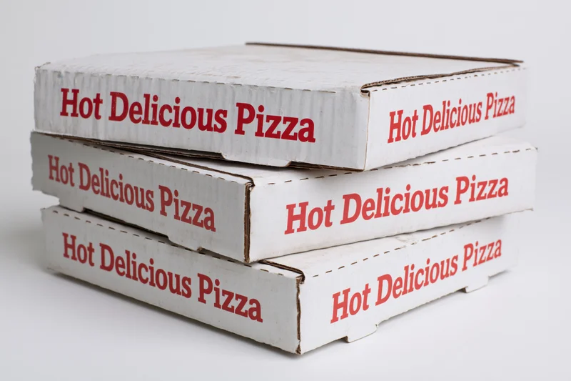 Three stacked white cardboard pizza delivery boxes with red text on a plain background