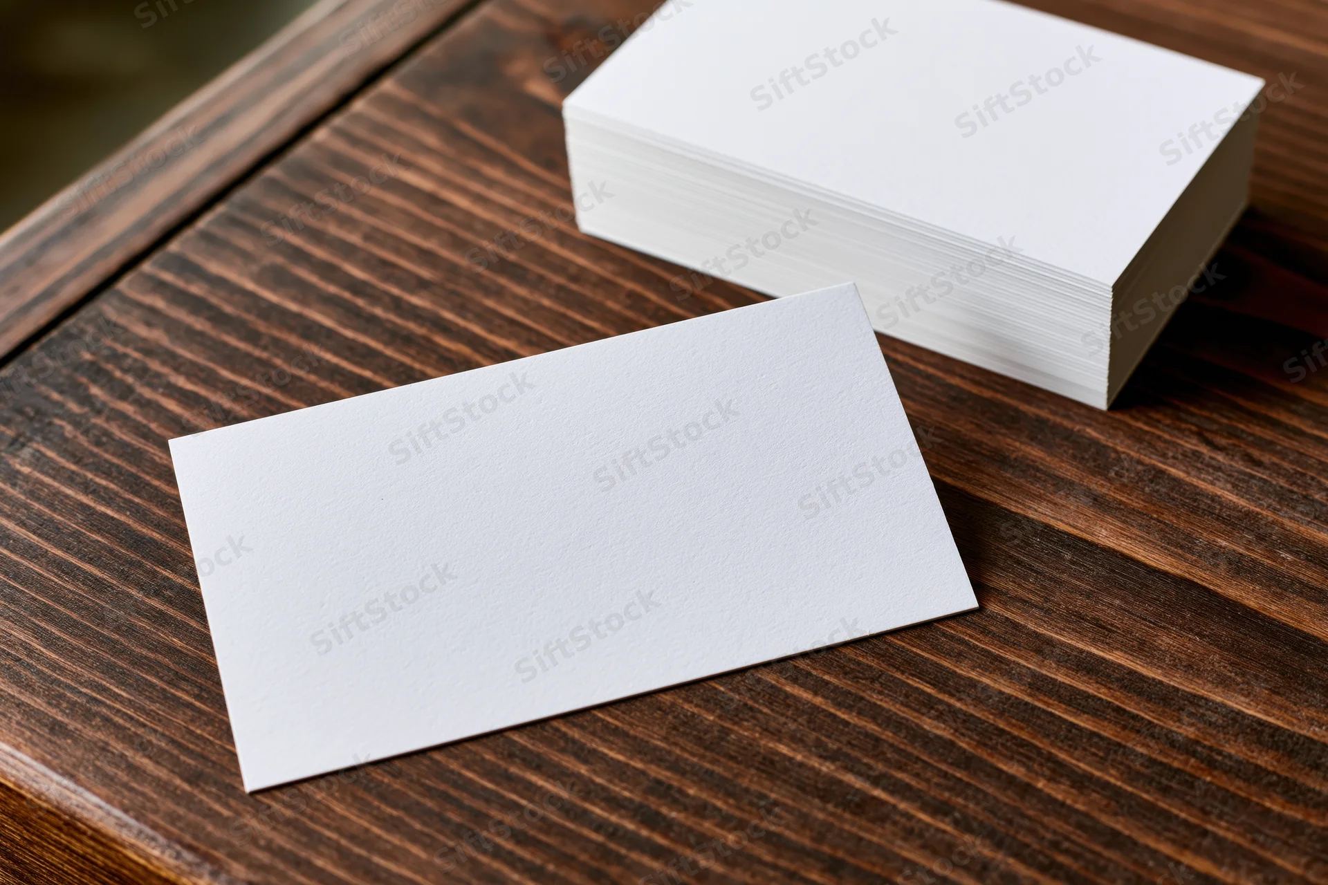 Blank white business cards arranged on dark wooden table
