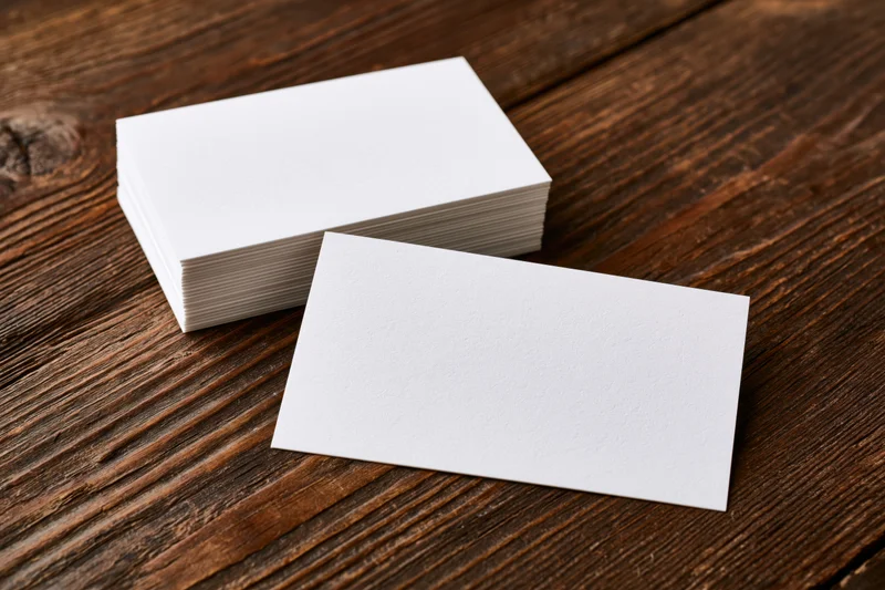 Blank business cards arranged on a dark wooden table