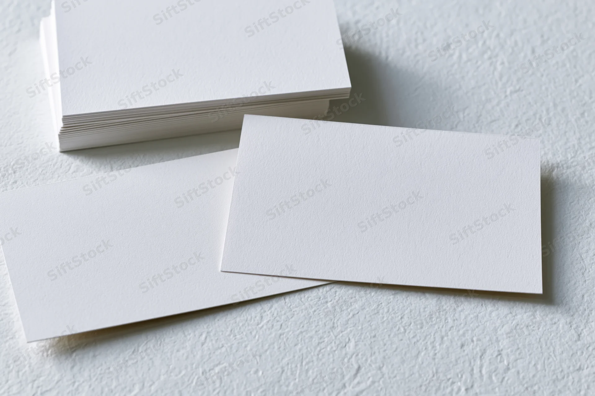 Blank white business cards arranged on textured white surface with copyspace