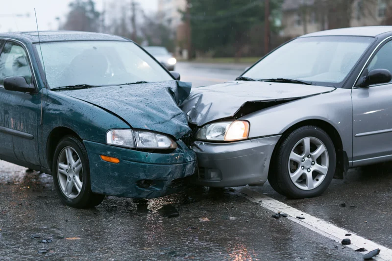 Two damaged cars collided head-on on a wet road in rainy weather