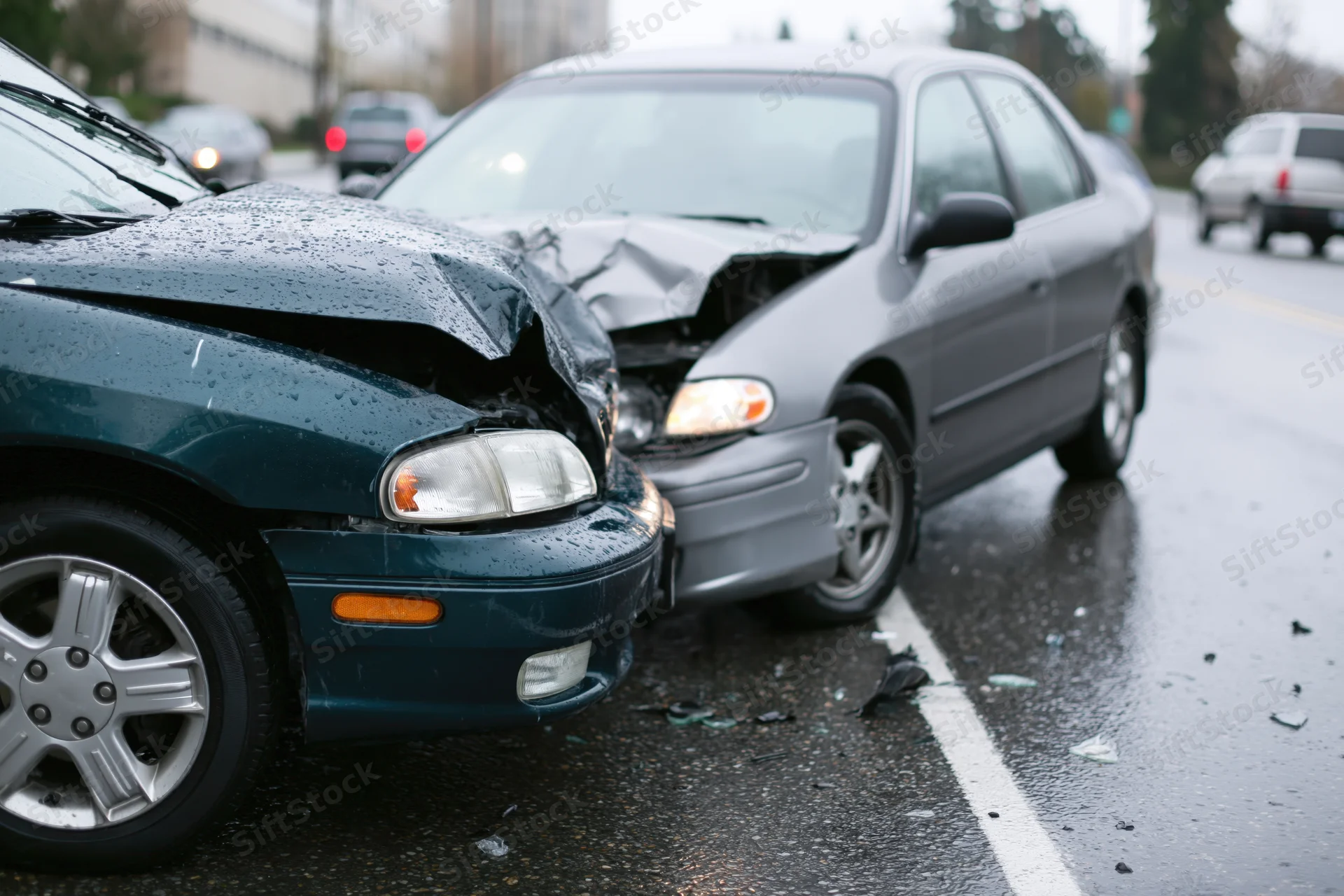 Two damaged cars locked together after front-end collision on wet road