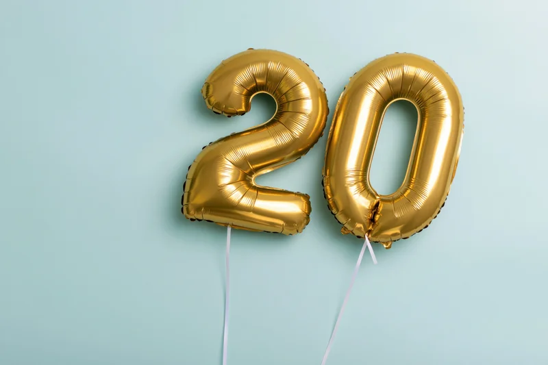 Two gold foil balloons forming 20 against blue background