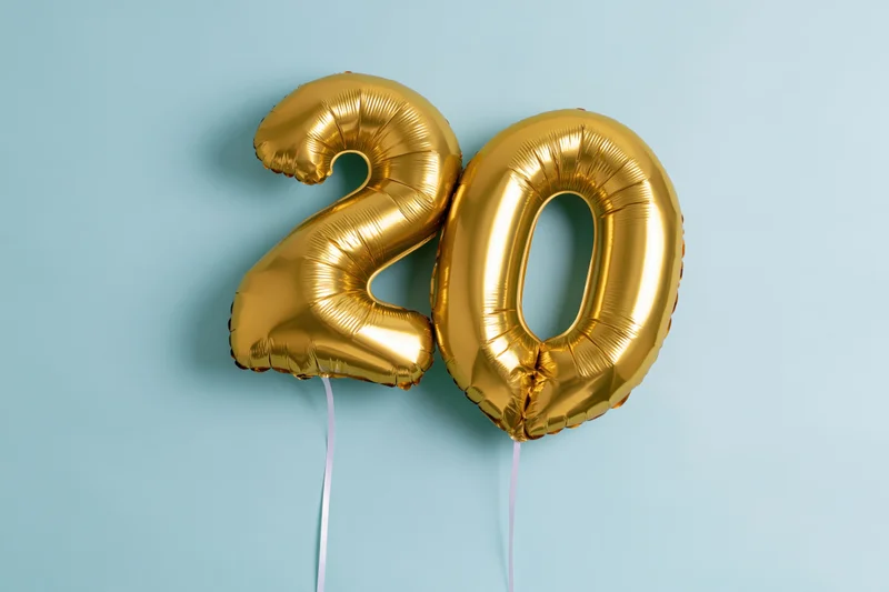 Two gold foil number balloons forming 20 over blue background