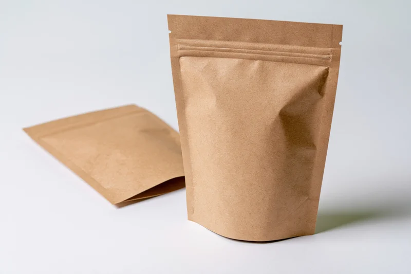 Two kraft paper resealable pouches standing on a white surface