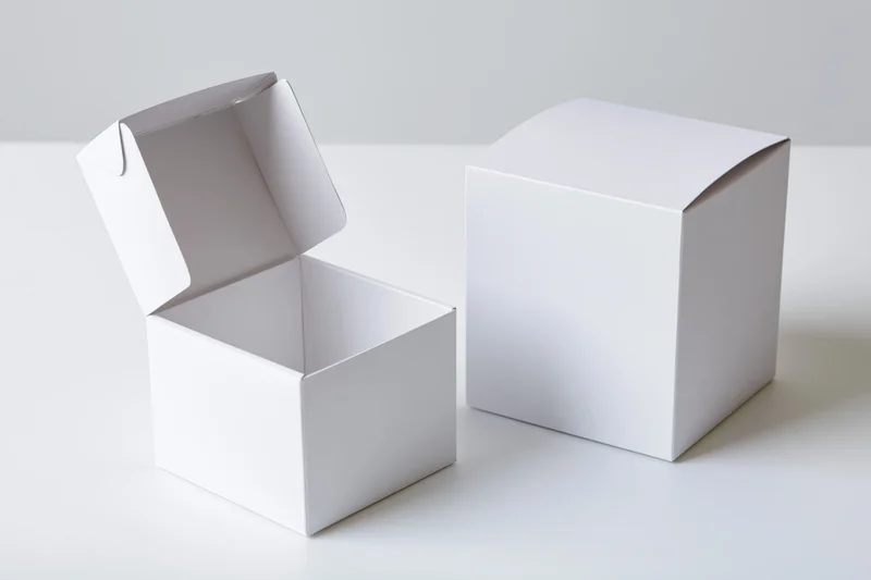 Two plain white cardboard flip-top boxes, one open and one closed, on a white surface
