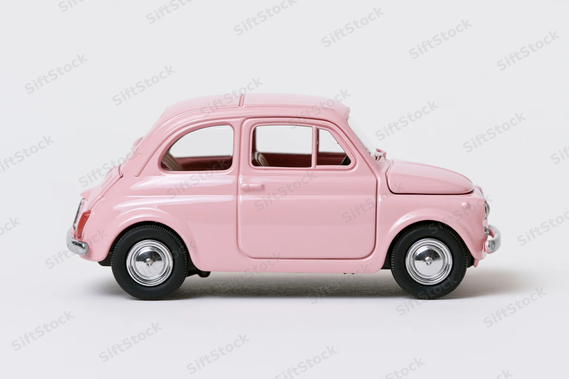 Pink vintage fiat 500 die-cast model car in side profile on white background