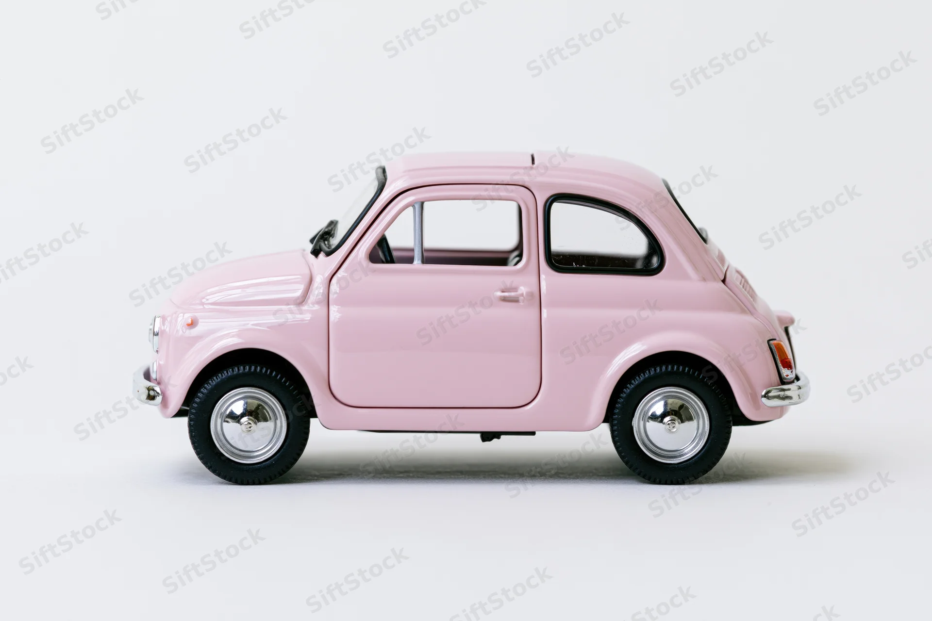 Pink vintage fiat 500 die-cast model car in profile view on white background