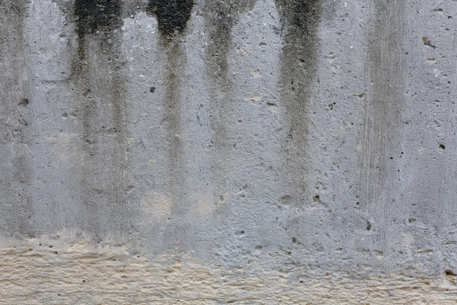 Weathered concrete wall surface with vertical stains and texture filling the frame