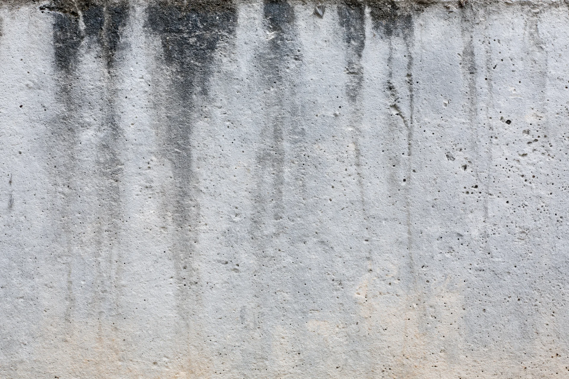 Weathered concrete wall surface filling the frame with vertical stains and rough texture
