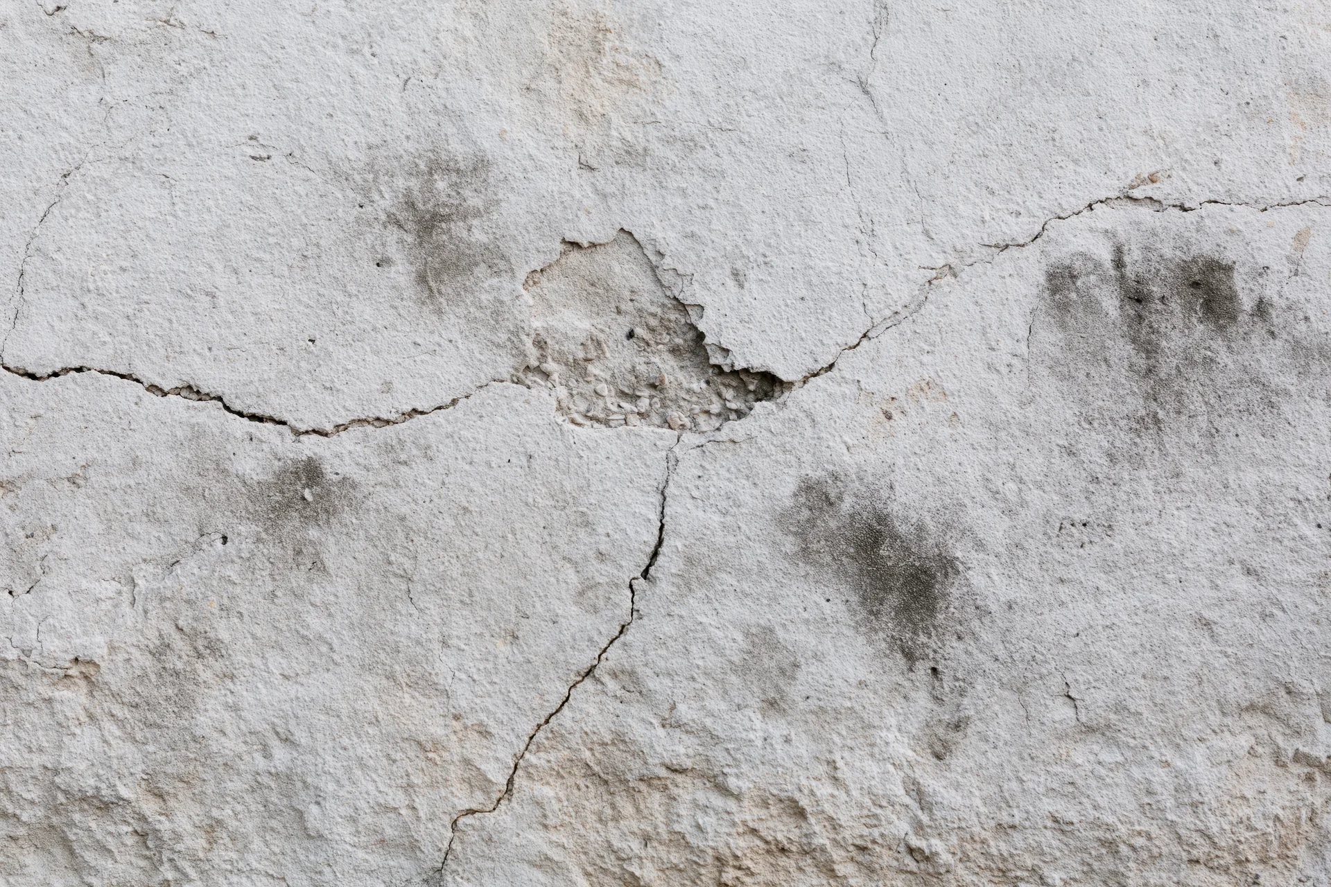 Weathered concrete wall surface with cracks and stains filling the frame