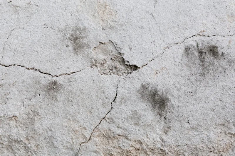 Weathered concrete wall surface with cracks and stains filling the frame