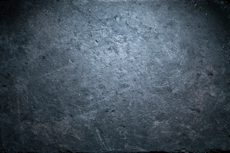 Weathered concrete wall surface filling the frame with dark vignette and visible cracks and scratches