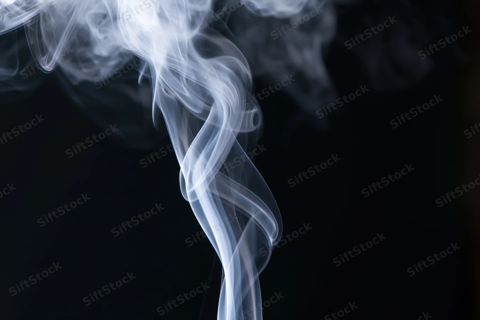 White smoke rising in delicate curls against a dark background
