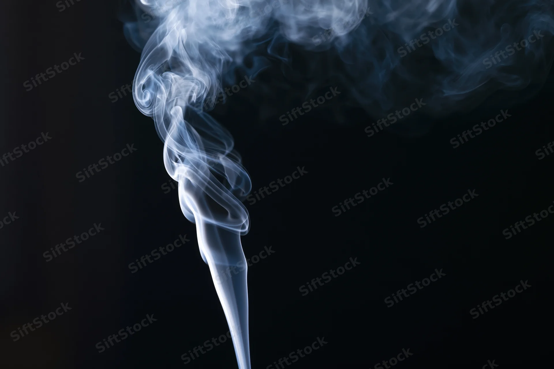 White smoke rising in delicate curls against a black background