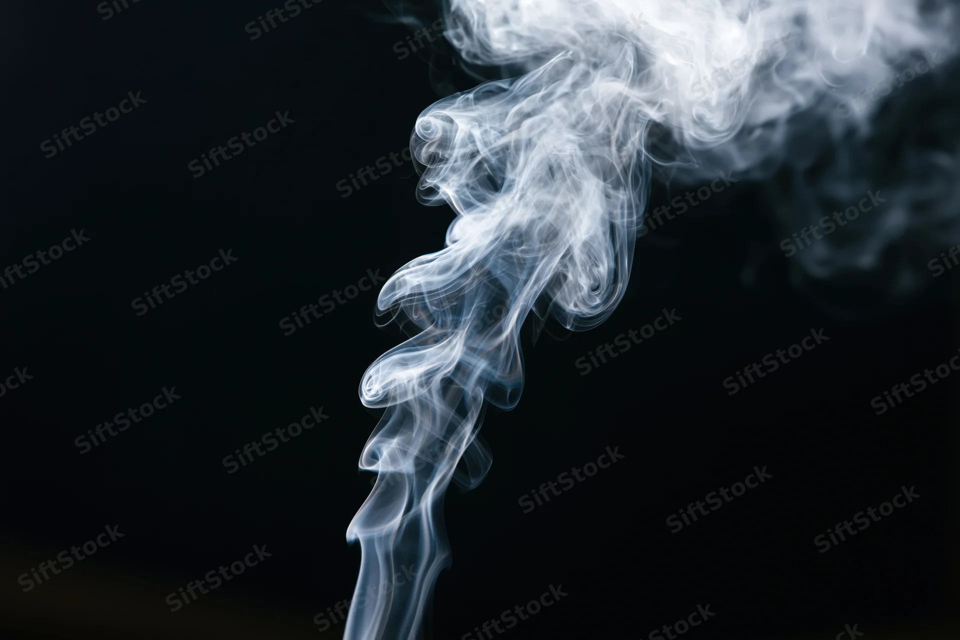 White smoke rising and curling upward in delicate twists against a dark background