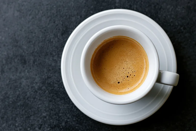 White ceramic espresso cup on a matching saucer filled with foam
