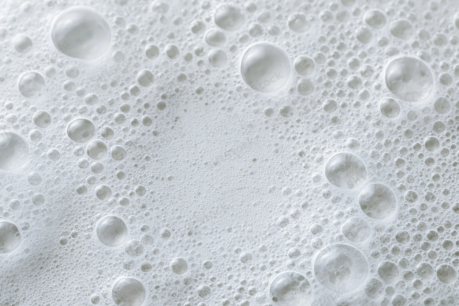 Closeup of white soap foam and bubbles scattered across a wet surface