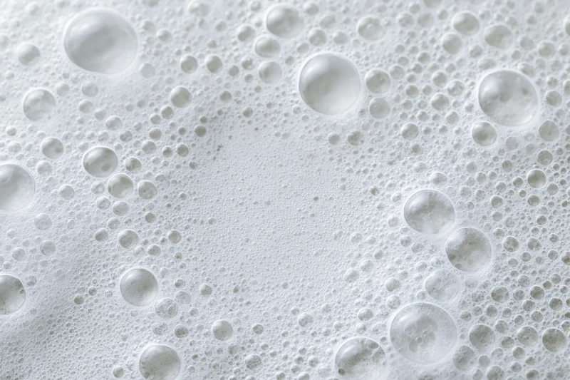 Closeup of white soap foam and bubbles scattered across a wet surface