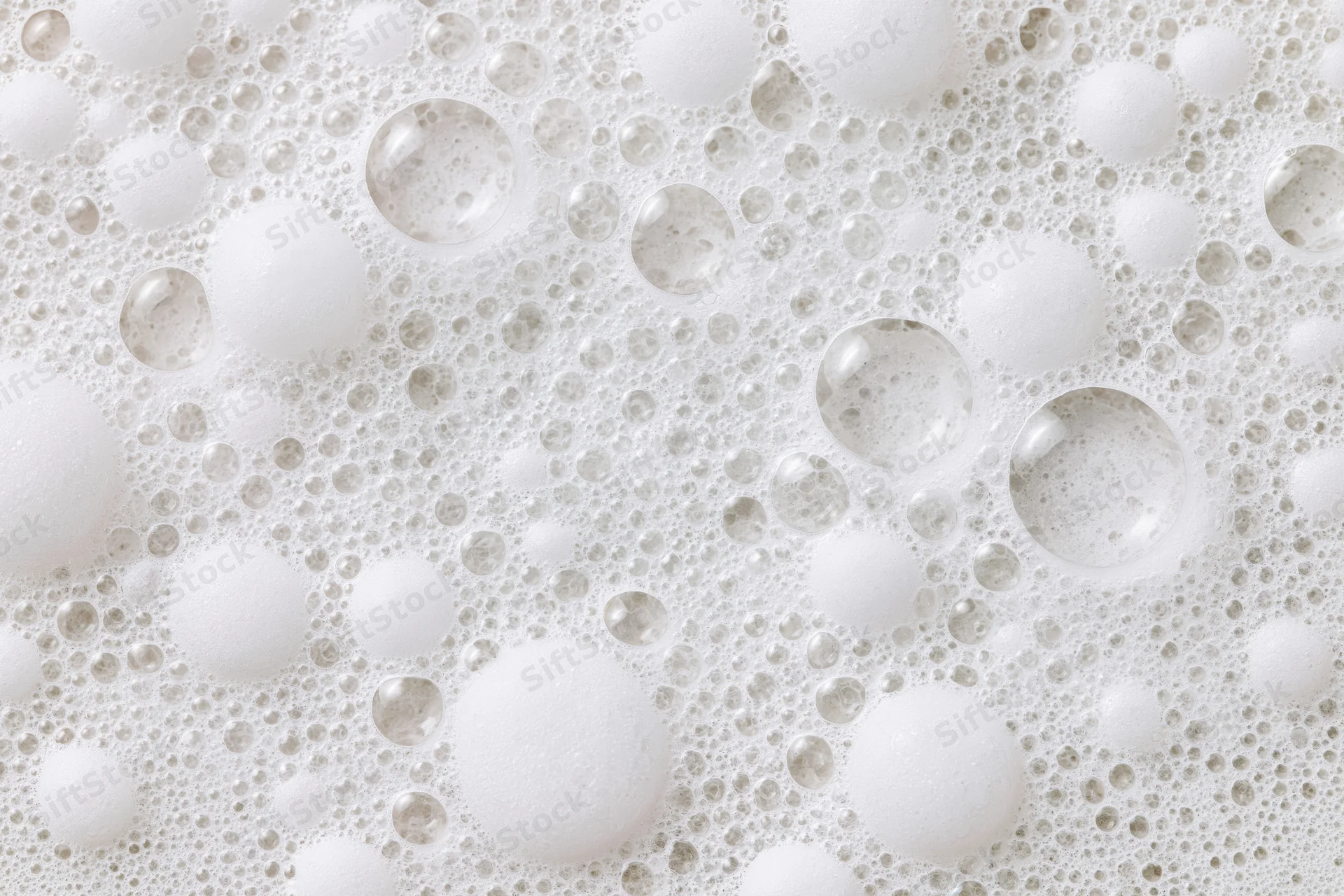 Closeup of white soap foam and bubbles scattered across a wet surface